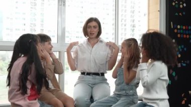 Farklı öğrencilerle çevrili yerde birlikte otururken, zeki beyaz bir öğretmen ders veriyor. Çok kültürlü bir öğrenciyle oynayan profesyonel bir eğitmen. Yaratıcı eğitim konsepti. Etkinlik.