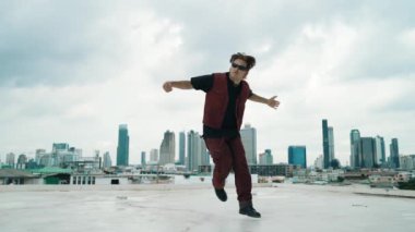B-boy dans gösterisi profesyonel sokak dansçısı çatıda gökyüzü dövüşçüsüyle, şehir manzaralı. Çekici Asyalı hippi gösterisi, hareketli adımlar. Açık hava sporu 2024. Hip-hop tarzı. hiphop.