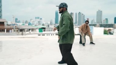 Profesyonel break dans takımı çatıda çok kültürlü arkadaşlar varken break dans alıştırması yapıyor. Genç modern dans grubu hip hop hareketi yapıyor. Tarz, moda, aksiyon. Açık hava sporu 2024 hiphop..