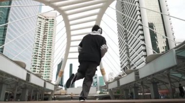 Genç Asyalı hippi şehir merkezinde insanların etrafında ayak izlerini gösteriyor. Şık bir sokak dansçısı B-boy ya da serbest dans eder. Açık hava sporu 2024. Break dans. Yumuşak bir şekilde..