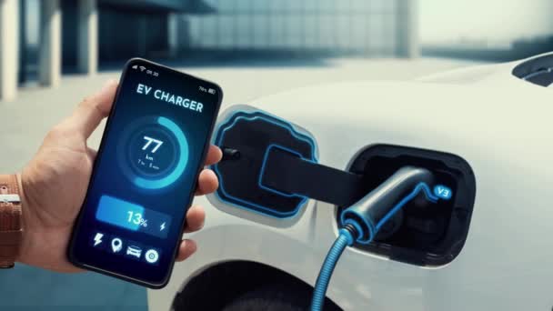 智能手机应用程序显示数字式电动车电池在屏幕上的状态 同时充电站 汽车利用的可持续和清洁替代能源概念 仔细阅读 — 图库视频影像