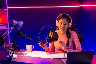 Geceleri podcast 'te olumlu konuşmalar yapan, pembe neon ışıklı modern stüdyoda sunum için dizüstü bilgisayar kullanan, gülümseyen, genç, güzel Asyalı bir etkileyiciydi. Taktik.