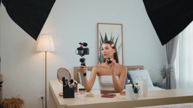 Sosyal medya için güzellik ve kozmetik video içeriği hazırlayan genç bir kadın. Güzellik blogcusu kameraya gülümserken seyircilere ve takipçilere güzellik bakımını gösteriyor. Düzenle