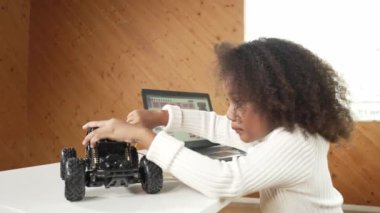 Akıllı Afrikalı kız dizüstü bilgisayar kullanırken ya da komut kodu yazarken kablo kullanırken robotik araba yapıyor. BTMM teknolojisi online sınıfında çalışan yetenekli bir bayan öğrenci. Etkinlik.