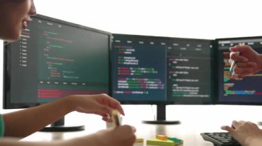Yavaş çekim arkası yazılım geliştirici mühendisi bilgisayar programlama için birlikte çalışarak hata ayıklama kodunu çözüyor, ofiste monitörde karmaşık algoritmaları çözüyor. Filizlenen
