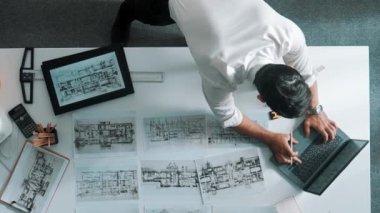 Bina yapısını analiz etmek için dizüstü bilgisayar kullanırken tablete bakan mühendislerin yukarıdan aşağı görüntüsü. Proje planıyla toplantı masasında iç tasarımı kontrol eden mimarın hava görüntüsü. Hizalama.