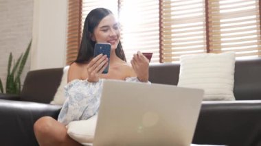 Genç bir kadın internet bankacılığı için kredi kartıyla dizüstü bilgisayar kullanıyor. Evinde online ödeme kapısı ile E ticareti yapıyor. Banka kartıyla modern ve kullanışlı online satın alma. Blithe