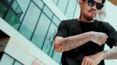 İspanyol hipster 'ın yakın çekimi alçak açılı kamerayla break dans yapıyor. Yetenekli break dansçı sokak dansı yapıyor ve gökyüzü kavgacı manzaralı müzikle dans ediyor. Break dans. Açık hava sporu 2024 hiphop..