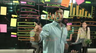 Cam duvarda istatistiksel mali grafiği olan pazarlama stratejisini işaret eden yetenekli bir işadamı. Profesyonel iş ekibi sunumu dinlerken müdür pazarlama fikrini paylaşıyor. İzleme