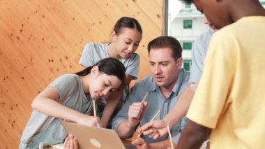 Akıllı robotlar sınıfta dizüstü bilgisayar ekranını işaret ederken, beyaz bir öğretmen yorum yapıyor ya da öğrencilere tavsiye veriyor. Öğretmen bilgisayar kullanırken çeşitli öğrencilerin ders verirken not alması. Öğretim