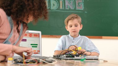 Kafkas akıllı çocuk kök teknoloji dersinde tornavida kullanarak ana tahtayı tamir ederken aynı zamanda gülümseyen öğrenci de dizüstü bilgisayar ekranı kodlu elektronik makineyi incelemek için birlikte çalışıyor. Pedagoji.