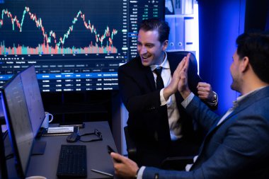 İki borsa simsarı borsa hisselerinden kar elde ediyor. İş yerindeki en yüksek neon ışığı noktasındaki monitörde finansal fayda verilerini gösteren başarılı borsa. Satılabilir.