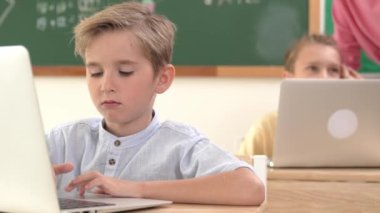 Çeşitli çocuklar yazılım sistemini programlarken beyaz çocuk dizüstü bilgisayarda çalışıyor. Öğretmen ve öğrenci sorunları çözmek ve kodlama mühendisliğini desteklemek için erkek bilgisayar ekranına bakıyor. Pedagoji.