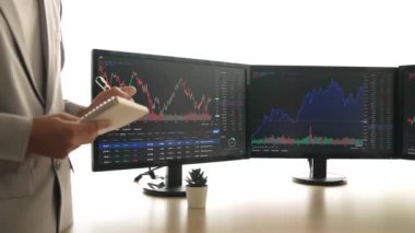 Menkul kıymetler borsası pazarlamasını inceleyen borsa yatırımcıları, zarar ve kazanç için mum bar fiyatlarını analiz eden monitörlere bakıyor. Filizlenen