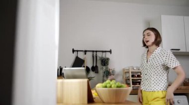 Kafkasyalı anne, modern mutfakta dizüstü bilgisayarda yemek tarifine bakarken salata yapmak için yemek hazırlıyor. Yetenekli ev bekçisi taze sebze kullanarak kahvaltı hazırlıyor. Pedagoji.
