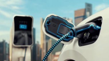 Elektrikli araba şarj istasyonuna bağlanır ve şehrin arka planında gelişmiş EV şarj cihazıyla şarj edilir. Gelecekteki yenilikçi çevre dostu enerji sürdürülebilirliği CO2 emisyonunu azaltmak için. İnceleyin