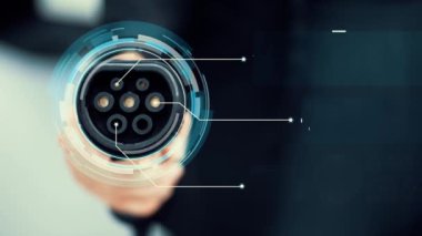 Kameranın önüne odaklanmış EV şarj cihazı fütüristik akıllı dijital EV batarya durum hologramını gösteriyor. EV araba şarjı sürdürülebilir güç için alternatif enerji kullanıyor. İnceleyin