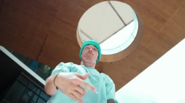 Beyaz tenli yakışıklı hippinin düşük açılı kamerası havalı poz verirken kameraya bakıyor. Serbest stil dansı yaparken şık bir dansçı gülümsemesi. Açık hava sporu 2024. Sokak dansı. hiphop.