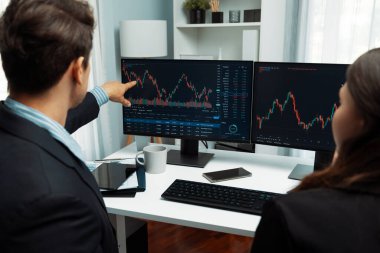 Dinamik borsada döviz kuru yatırımını tartışan iki ticaret simsarı iki bilgisayar ekranında gerçek zamanlı risk grafiği ya da modern ofisteki kar noktasını karşılaştırıyor. Varsayım.