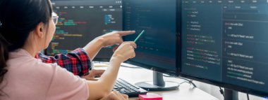 Kadın programcı bilgisayarda gösterilen kodu işaret ederken açıklıyor. Profesyonel programcı modern şirket ofisinde veri analizi ve Java betiği sunar. - Yakın çekim. Filizlenen.