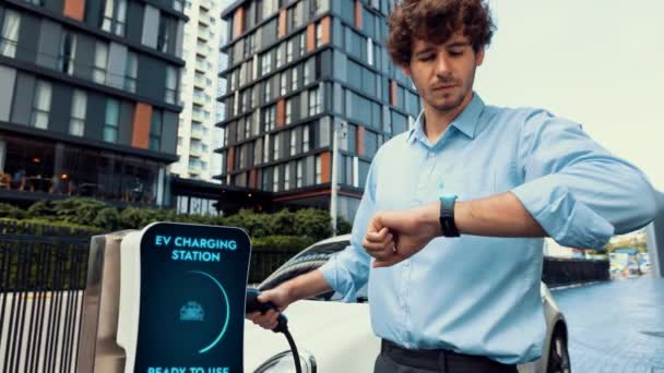 Podnikatel Kontroluje Stav Baterie Elektromobilu Hologramu Smartwactch Při Dobíjení Nabíjecí — Stock video