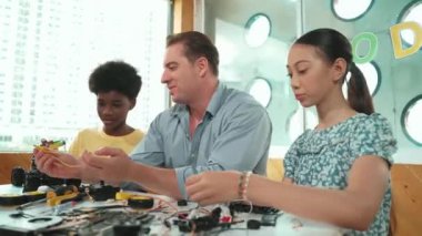 Yetenekli öğretmen Afrikalı çocuğa elektrikli aletleri açıklarken liseli kız model tamir ediyor. Çok kültürlü bir öğrenci robot araba yapımı ve elektronik aletleri öğreniyor. Öğretim