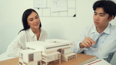 Profesyonel akıllı iş birliği mühendisi mühendis ekibi modern ofisteki ev yapısını planla kontrol ederken genç ve güzel proje yöneticisi not alıyor. Yaratıcı tasarım konsepti. Tertemiz...