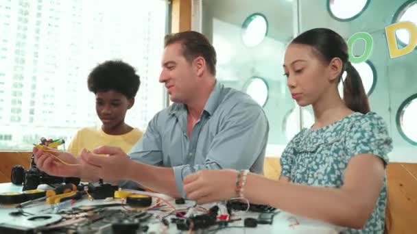 선생님은 고등학교 소녀가 모델을 고치는 아프리카 소년에게 장비에 설명합니다 다문화 — 비디오