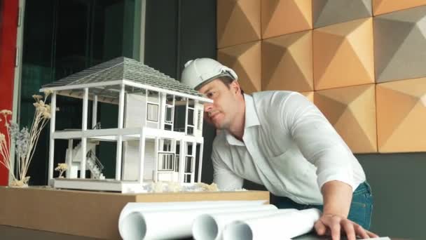 专业的高加索男性建筑工程师用项目计划和建筑模型对房屋模型的建造进行检查和检查 商业设计概念 机械手 — 图库视频影像