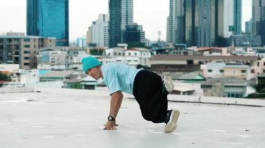 Profesyonel beyaz dansçı, şehir ya da şehirle çatıda sokak dansı yapıyor. Genç adamın sokak dansı yaparken dondurucu poz vermesi. Açık hava sporu 2024 hiphop..
