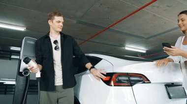 Elektrikli araba sürücüsü, arabadaki uygulama ekranında şarj durumu, menzil ve şarj limitini kontrol ediyor. Akıllı teknoloji aygıtı, EV arabasının araba aküsündeki elektrik depolama verilerini şarj ettiğini gösteriyor..