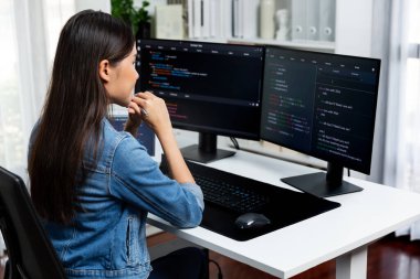 Genç Asyalı bilişim geliştiricisi güzel poz için online bilgi topluyor. Kodlama programı verileriyle birlikte kotlu tişört giyiyor. Güvenlik analizi ile çevrili iki ekran. Taktik.