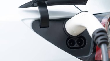 Elektrikli araç portuna bağlı EV şarj prizi kolu şarj istasyonundan şarj oluyor. Modern tasarlanmış EV araba ve daha iyi bir gelecek için temiz enerji sürdürülebilirliği. Panorama Senkronları