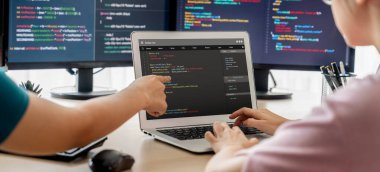Bilgisayar ekranında program kodu gösterilirken iki akıllı kooperatif bilgisayar mühendisi program kodunu çözmek için takım çalışması yapıyor. Laptop, web geliştirme, programcı, Java betiği. Filizlenen.