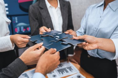 Şirket çalışanı, yapboz parçalarını masa üzerindeki raporlara ortaklık ve takım çalışması olarak bağlıyor. Yapboz 'u birleştirerek iş dünyasındaki birlik ve sinerji. Uyum