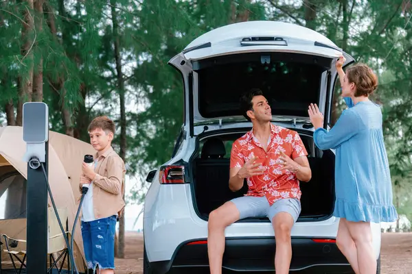 stock image Outdoor adventure and family vacation camping in nature travel by eco friendly car for sustainable future. Lovely family recharge EV car with EV charging station in campsite. Perpetual