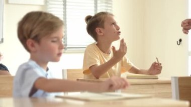 Beyaz bir çocuk ödevlerini yaparken ve açıklama dinlerken güzel bir öğretmen sınavı açıklıyor. Sınıfta not alırken ya da kağıda cevap yazarken öğretmenine bakan sevimli bir çocuk. Pedagoji.