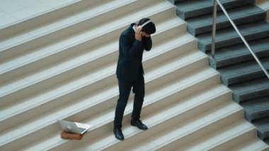 Kulaklıktan müzik eşliğinde merdivenlerde duran profesyonel bir iş adamı. Merdivenlere dizüstü bilgisayar yerleştirip dans ederken dinlenme sesi dinleyen yetenekli bir proje yöneticisi. Modern dans. Sevinçli..