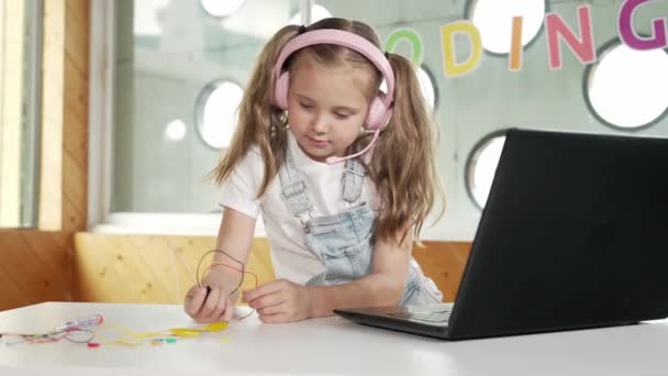 電子機器を勉強しながらヘッドフォンをかぶっている可愛い女の子 ラップトップ スクリュードライバー ワイヤーをテーブルの近くに置きながら 科学実験を行っている白人の子供 スマートなオンライン教室 エラー — ストック動画