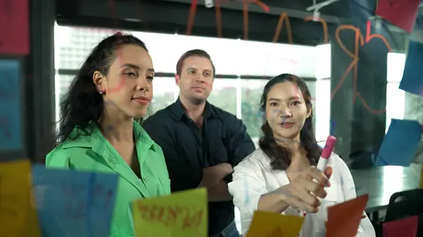 专业多元化的商业团队在玻璃板上粘贴着五颜六色的便条 展示了他们头脑风暴的营销理念 西班牙裔项目经理将业务策略写在笔记上 机械手 — 图库照片
