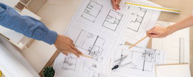 Mimari planlar toplantı masasında dağıtılırken profesyonel mimar el çabukluğu planlara işaret ediyor. Yaratıcı tasarım takım çalışması tartışma konsepti. Üst Manzara. Filizlenen.