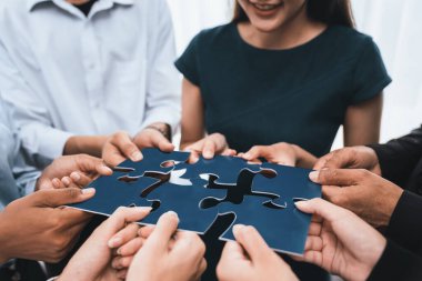 Çeşitli şirket çalışanları, ortaklık ve takım çalışmasını temsil etmek için bulmaca parçalarını birleştirerek ofiste işbirliği yapıyor. Yapboz 'u birleştirerek iş dünyasındaki birlik ve sinerji. Uyum