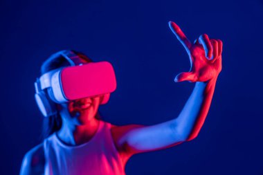 Etrafı neon ışıklı kulaklıklarla çevrili bir kadın metaevreni bağlayan VR kulaklık takıyor, fütüristik siber uzay topluluk teknolojisi yayıyor, işaret ve başparmak ile sanal nesne etkileşimi kuruyor. Halüsinasyon.