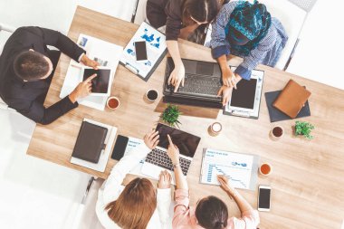 Modern ofisteki iş adamları ve iş kadınlarıyla grup toplantısındaki iş adamlarının en üst düzey görüşü, masada dizüstü bilgisayar, kahve ve belge ile. Kurumsal şirketler uds