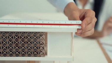 Profesyonel erkek mühendis ev modelini cetvel kullanarak ölçerken güzel bir kooperatif iş arkadaşı verileri analiz etmek için dizüstü bilgisayar kullanarak birlikte çalışıyor. Yaratıcı tasarım ve takım çalışması. - Yakın çekim. Tertemiz..