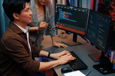 Bilgi teknolojisi geliştiricileri modern ofisteki neon ışık odasında verileri çevrimiçi olarak çalıştıran akıllı web sitesi geliştirme kodlayıcı sistemine işaret ediyorlar. İnfobahn.