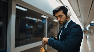 Proje yöneticisi tren istasyonunda şarkı seçmek için cep telefonu tutarken kulaklık takıyor. Zeki iş adamı bulanık bir geçmişi olan treni beklerken rahatlatıcı müzik dinliyor. Sevinçli..