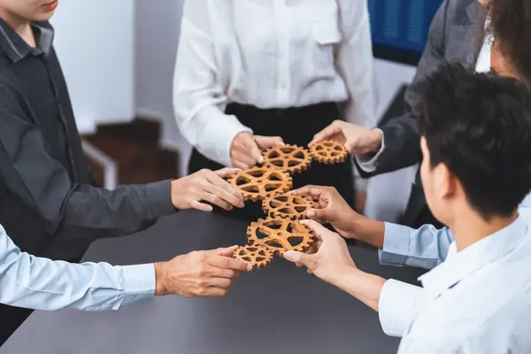 Office worker holding cog wheel as unity and teamwork in corporate workplace concept. Diverse colleague business people showing symbol of visionary system and mechanism for business success. Concord