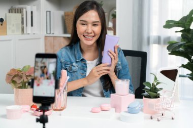 Genç ve güzel Asyalı bir kız nemlendirici vücut kremi ürününü inceleyerek sosyal medyada canlı cilt testi yaparak modern odada en çok satanlarla canlı telefon kaydı yapıyor. Taktik.