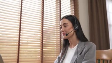 Kadın çağrı merkezi operatörü ya da müşteri hizmetleri çalışanı, müşteriye yardım etmek için kulaklıkla konuşurken çalışma alanı üzerinde çalışıyor. Profesyonel modern iş hizmeti. Blithe